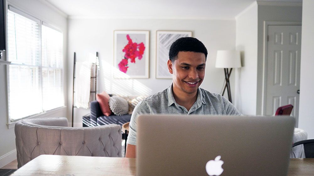 Young man sitting at laptop at home taking an online assessment exam