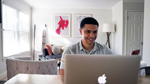 Young man sitting at laptop at home taking an online assessment exam