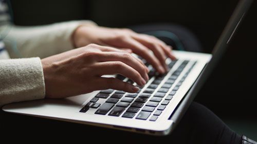 image of hands working on a laptop doing a remotely invigilated exam