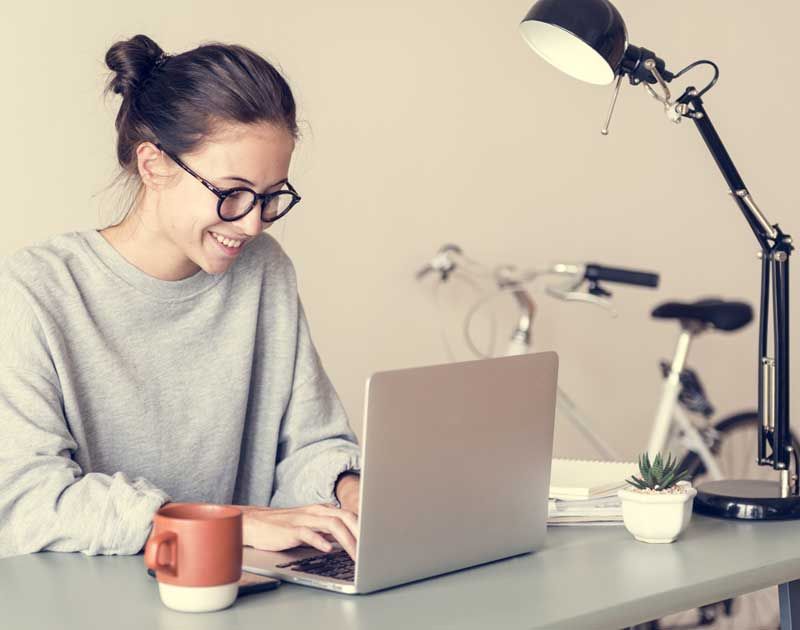 Woman taking a remotely invigilated exam from home on a laptop