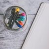 Pens in a jar beside a notebook