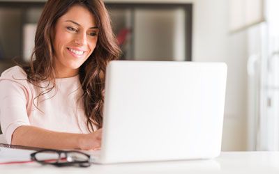 Female exam candidate using online assessment to sit exam on a laptop